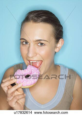 Young woman eating doughnut View Large Photo Image Picture - Young woman eating doughnut. Fotosearch
