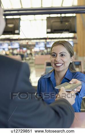 Stock Image - Airline check-in attendant giving a passport to a man at a counter. Fotosearch