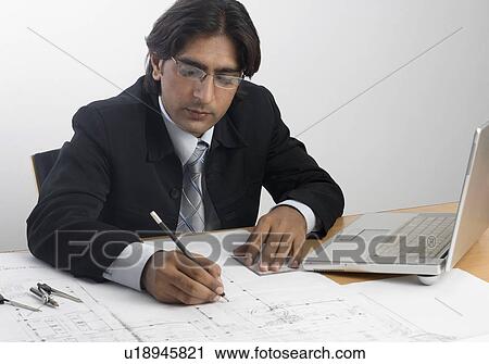 Stock Image - Architect drawing with a pencil on a blueprint. Fotosearch
