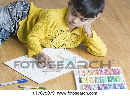 Boy lying on the hardwood floor and drawing with crayons View Large Photo Image Stock Photo - Boy lying on the hardwood floor and drawing with crayons. Fotosearch