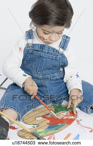 Stock Image - Boy sitting and holding a paintbrush. Fotosearch