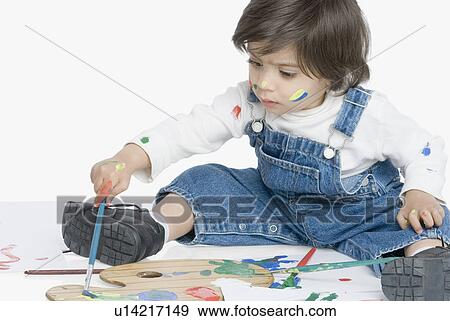 Boy sitting and painting with a paintbrush View Large Photo Image Stock Photo - Boy sitting and painting with a paintbrush. Fotosearch