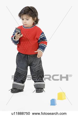 Boy standing and looking at a mobile phone View Large Photo Image Stock Image - Boy standing and looking at a mobile phone. Fotosearch