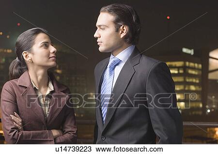 Stock Image - Businessman and a businesswoman looking at each other. Fotosearch