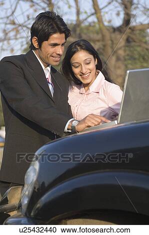 Stock Image - Businessman and a businesswoman using a laptop. Fotosearch