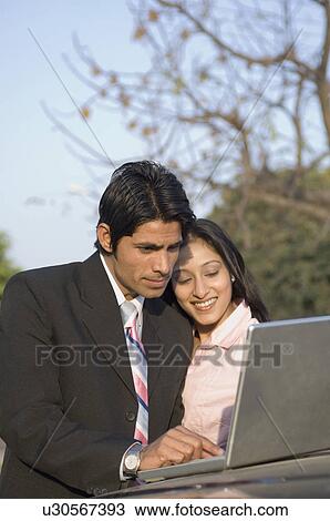 Stock Image - Businessman and a businesswoman using a laptop. Fotosearch