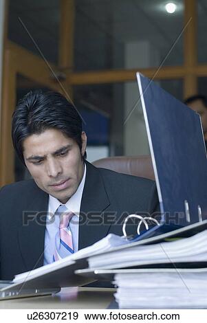 Businessman looking at a file in an office View Large Photo Image Stock Photo - Businessman looking at a file in an office. Fotosearch