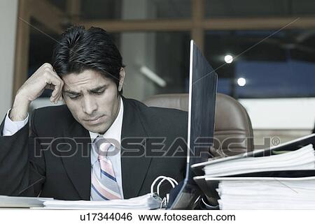 Stock Photograph - Businessman looking at a file in an office. Fotosearch