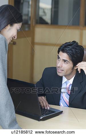 Businessman using a laptop and looking at a businesswoman View Large Photo Image Stock Image - Businessman using a laptop and looking at a businesswoman. Fotosearch