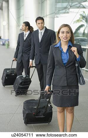 Businesswoman and two businessmen standing with their luggage View Large Photo Image Stock Image - Businesswoman and two businessmen standing with their luggage. Fotosearch