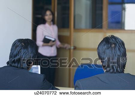 Stock Image - Businesswoman standing in front of two businesswomen in an office. Fotosearch