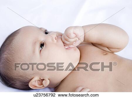 Stock Image - Close-up of a baby girl sucking her thumb. Fotosearch
