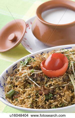 Picture - Close-up of a bowl of fried rice with a bowl of curd on a plate. Fotosearch