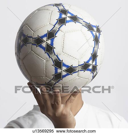 Stock Photography - Close-up of a boy covering his face with a soccer ball. Fotosearch