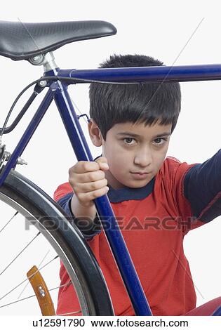 Stock Image - Close-up of a boy holding a bicycle. Fotosearch