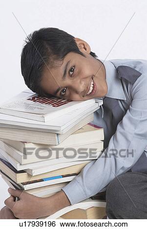 Stock Photograph - Close-up of a boy holding books and smiling. Fotosearch