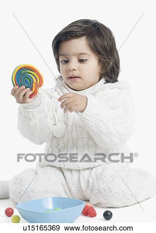 Close-up of a boy looking at a lollipop View Large Photo Image Stock Photo - Close-up of a boy looking at a lollipop. Fotosearch