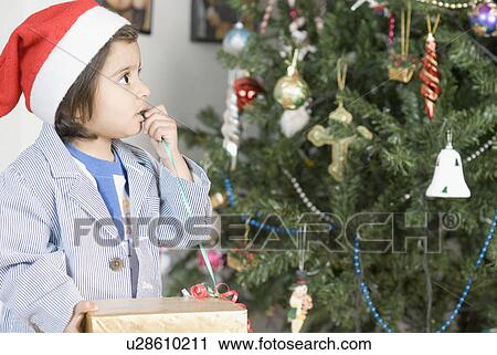 Stock Image - Close-up of a boy looking at a Christmas tree. Fotosearch