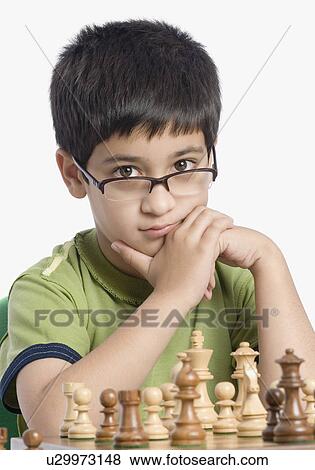 Stock Photo - Close-up of a boy playing chess with his hand on his chin. Fotosearch