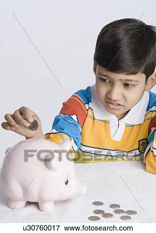 Close-up of a boy putting a coin in a piggy bank View Large Photo Image Stock Photo - Close-up of a boy putting a coin in a piggy bank. Fotosearch