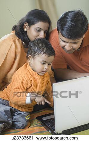Close-up of a boy sitting in front of a laptop with his parents View Large Photo Image Stock Image - Close-up of a boy sitting in front of a laptop with his parents. Fotosearch