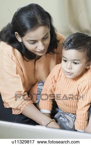 Close-up of a boy sitting in front of a laptop with his mother View Large Photo Image Stock Photo - Close-up of a boy sitting in front of a laptop with his mother. Fotosearch