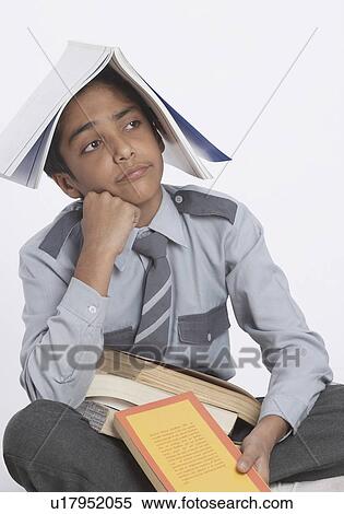 Stock Photography - Close-up of a boy sitting with his hand on his chin. Fotosearch