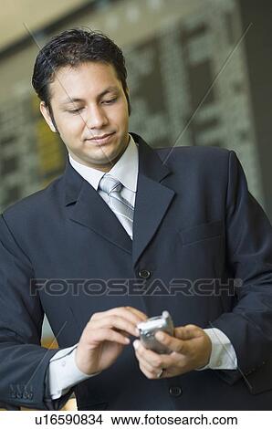 Close-up of a businessman holding a mobile phone View Large Photo Image Picture - Close-up of a businessman holding a mobile phone. Fotosearch