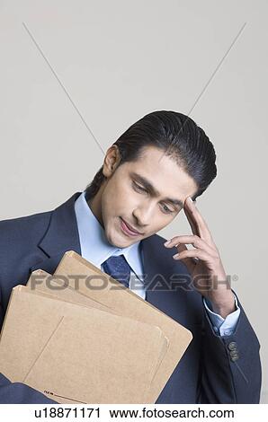 Close-up of a businessman holding a file and thinking View Large Photo Image Stock Image - Close-up of a businessman holding a file and thinking. Fotosearch