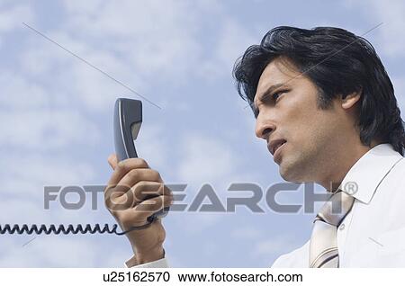 Stock Image - Close-up of a businessman holding a telephone receiver. Fotosearch