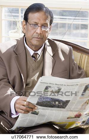 Stock Image - Close-up of a businessman reading a newspaper. Fotosearch