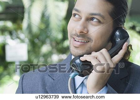 Close-up of a businessman talking on a pay phone View Large Photo Image Stock Photo - Close-up of a businessman talking on a pay phone. Fotosearch