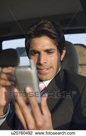 Stock Image - Close-up of a businessman using a personal data assistant in a car. Fotosearch