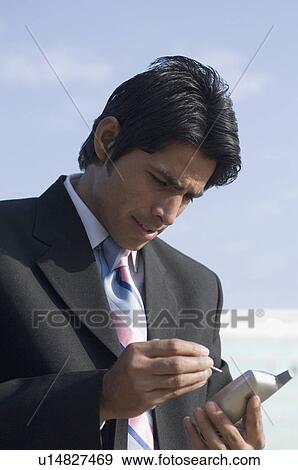 Stock Photo - Close-up of a businessman using a personal data assistant. Fotosearch