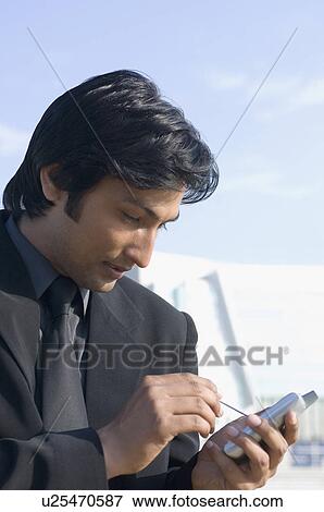 Stock Photo - Close-up of a businessman using a personal data assistant. Fotosearch