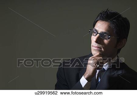 Stock Image - Close-up of a businessman wearing eyeglasses and thinking. Fotosearch