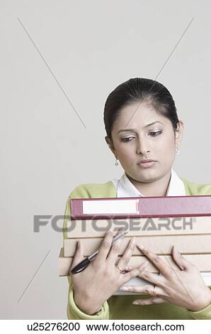 Stock Image - Close-up of a female office worker holding a pen and files. Fotosearch