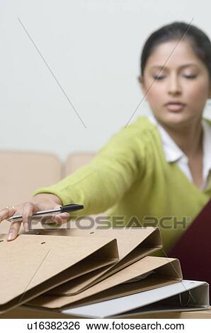 Stock Photograph - Close-up of a female office worker reaching for a file. Fotosearch