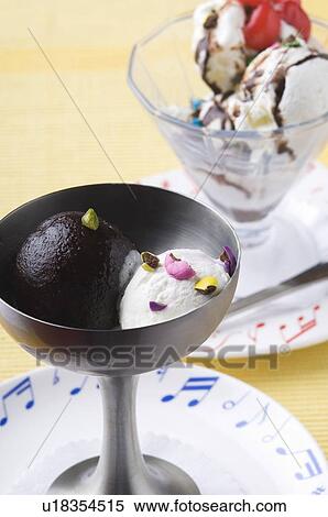 Stock Photography - Close-up of a gulab jamun and an ice cream sundae in bowls. Fotosearch