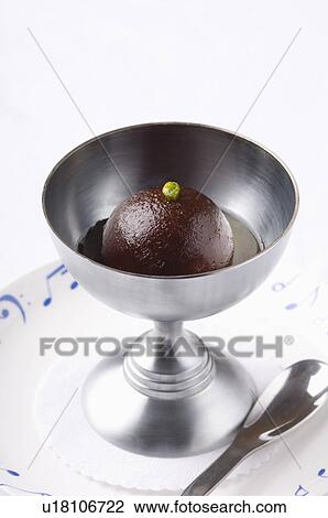 Stock Image - Close-up of a gulab jamun in a bowl with a spoon on a plate. Fotosearch