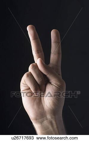 Stock Image - Close-up of a man's hand making a peace sign. Fotosearch
