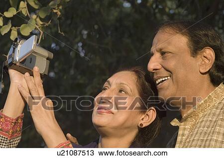 Close-up of a mature woman holding a video camera with a mature man smiling beside her View Large Photo Image Stock Image - Close-up of a mature woman holding a video camera with a mature man smiling beside her. Fotosearch