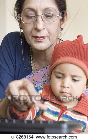 Close-up of a mature woman teaching her grandson how to use computer keyboard View Large Photo Image Picture - Close-up of a mature woman teaching her grandson how to use computer keyboard. Fotosearch