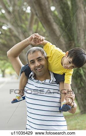 Stock Photo - Close-up of a mid adult man carrying his son on his shoulders. Fotosearch