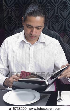 Stock Image - Close-up of a mid adult man looking at a menu in a restaurant. Fotosearch