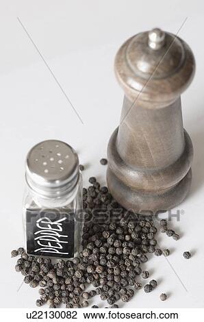 Stock Image - Close-up of a peppermill and a pepper shaker with peppercorns. Fotosearch