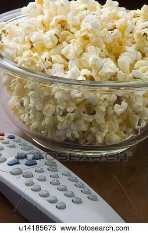 Stock Photography - Close-up of a remote control and popcorn in a bowl. Fotosearch