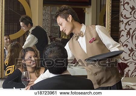 Close-up of a waiter serving wine to a young couple View Large Photo Image Stock Image - Close-up of a waiter serving wine to a young couple. Fotosearch