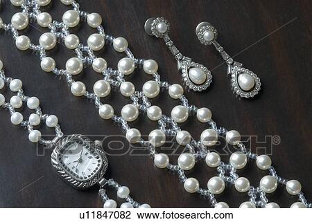 Stock Image - Close-up of a wristwatch with a bracelet and a pair of earrings. Fotosearch