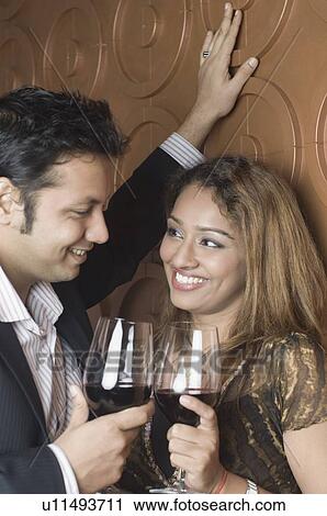 Stock Image - Close-up of a young couple holding wine glasses and looking at each other. Fotosearch